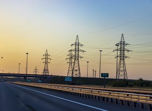 Highway in bright sunlight, power line illuminated by the sun. A beautiful landscape in the golden hour