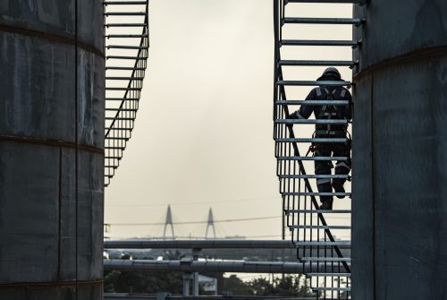 A male walking the upstairs inspection visual record storage tank oil stairs