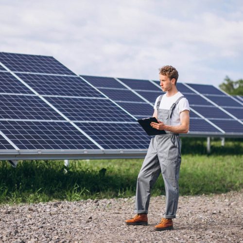 Man worker in the firld by the solar panels
