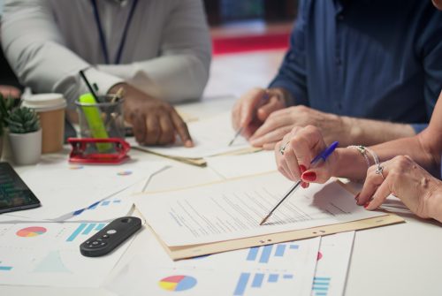 Mature person signing a contract with insurance agency banker, agreeing to the new pension plan contract with expert. Retired man collaborating with advisor to secure his life savings. Camera B.