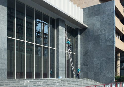Male worker in overalls professional glass cleaner washer
