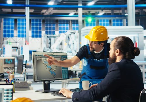 Photovoltaics factory manager with disability in wheelchair gives worker. Solar panels plant supervisor with paraplegia in inclusive workspace talking with employee, camera A